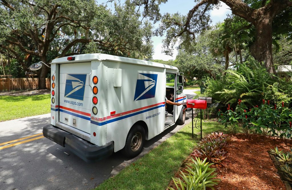mail carrier puts mail in a mail box